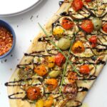 This Vegan Eggplant & Hummus Flatbread combines thin slices of eggplant, creamy hummus and balsamic cherry tomatoes & garlic. A great snack to share or a dinner to eat on your own | ThisSavoryVegan.com #vegan #veganpizza