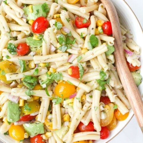This Tomato Corn Avocado Pasta Salad is filled with fresh ingredients and topped with a light and zesty dressing. Perfect party side dish | ThisSavoryVegan.com #thissavoryvegan #vegan #partyfood