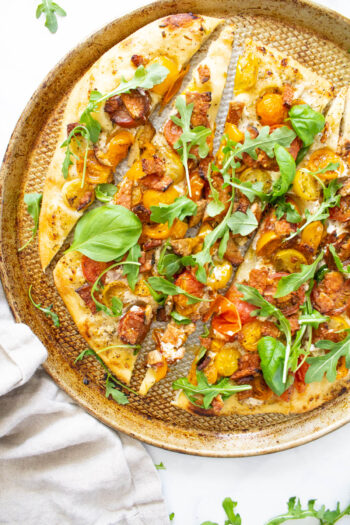 This Vegan BLT Pizza is layered with a rosemary cream sauce, heirloom cherry tomatoes, tempeh bacon and arugula. A fun twist on a classic | ThisSavoryVegan.com #thissavoryvegan #veganpizza #blt