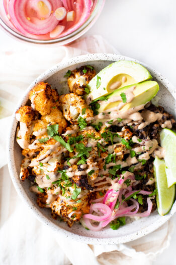 These Roasted Cauliflower Burrito Bowls are loaded with cilantro lime rice, black beans, smoky cauliflower and a chipotle yogurt sauce | ThisSavoryVegan.com #thissavoryvegan #roastedcauliflower #burritobowls