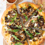 This Vegan Mushroom & Shallot White Pizza is better than takeout! Plenty of herbs, sun-dried tomatoes, creamy sauce & caramelized mushrooms | ThisSavoryVegan.com #thissavoryvegan #veganpizza #veganwhitepizza
