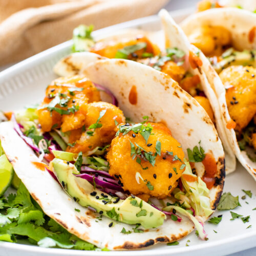 These Vegan Bang Bang Cauliflower Tacos are slightly spicy and a whole lotta delicious! A tangy slaw, crispy cauliflower and avocado slices | ThisSavoryVegan.com #thissavoryvegan #vegantacos #cauliflowertacos