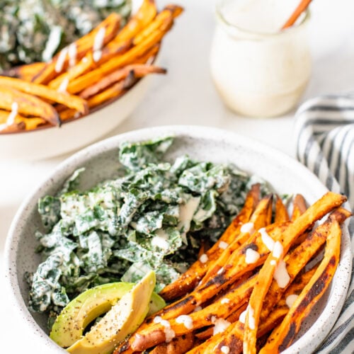 This Tahini Kale Caesar with Sweet Potato Fries is the perfect weeknight dinner. Crispy baked fries, vegan kale caesar and slices of avocado | ThisSavoryVegan.com #thissavoryvegan #kalecaesar #vegandinnerideas
