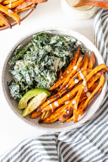 This Tahini Kale Caesar with Sweet Potato Fries is the perfect weeknight dinner. Crispy baked fries, vegan kale caesar and slices of avocado | ThisSavoryVegan.com #thissavoryvegan #kalecaesar #vegandinnerideas