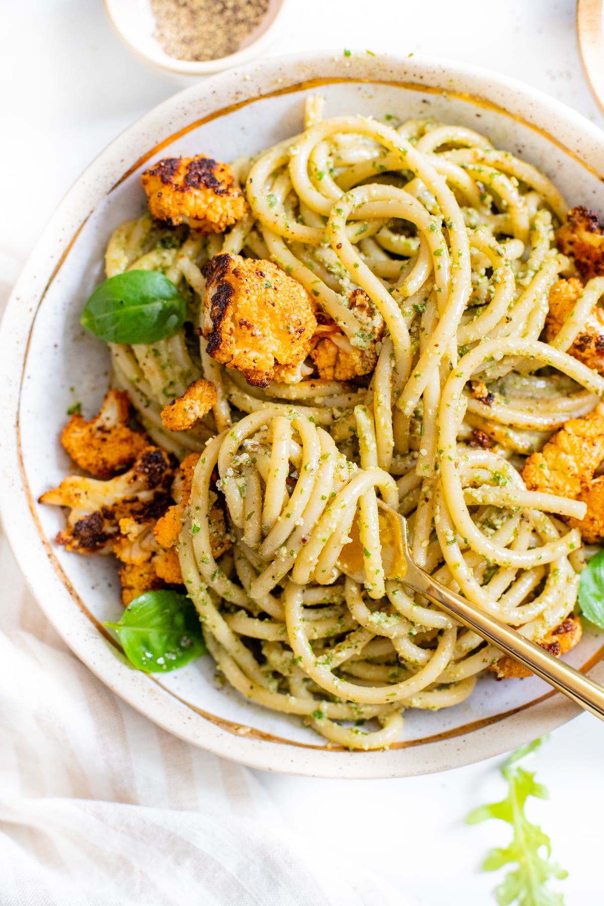 This Vegan Pesto Bucatini with Crispy Cauliflower is a quick and easy vegan dinner! Homemade argula-basil pesto & seasoned baked cauliflower over a bed of pasta | ThisSavoryVegan.com #thissavoryvegan #veganpesto #veganpasta