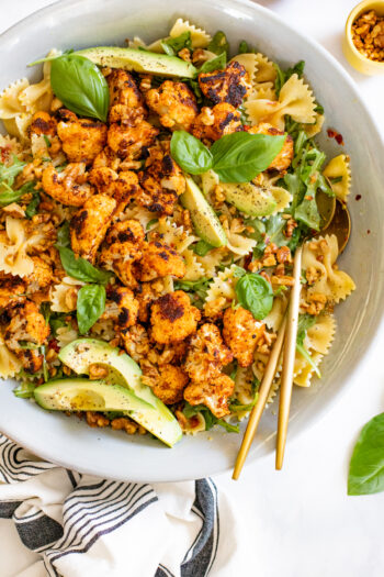 This Crispy Cauliflower Pasta Salad is served with a lemon & shallot vinaigrette, avocado slices, toasted walnuts, arugula & sun-dried tomatoes! | ThisSavoryVegan.com #thissavoryvegan #pastasalad #summersalad