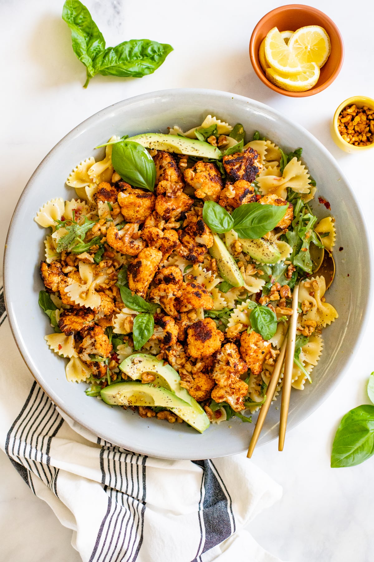 This Crispy Cauliflower Pasta Salad is served with a lemon & shallot vinaigrette, avocado slices, toasted walnuts, arugula & sun-dried tomatoes! | ThisSavoryVegan.com #thissavoryvegan #pastasalad #summersalad