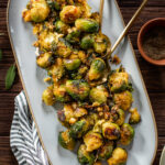These Crispy Vegan Smashed Brussels Sprouts are boiled, smashed, then roasted until crispy and delicious. Made with shallots and vegan parmesan | ThisSavoryVegan.com #thissavoryvegan #smashedbrusselssprouts #veganthanksgiving