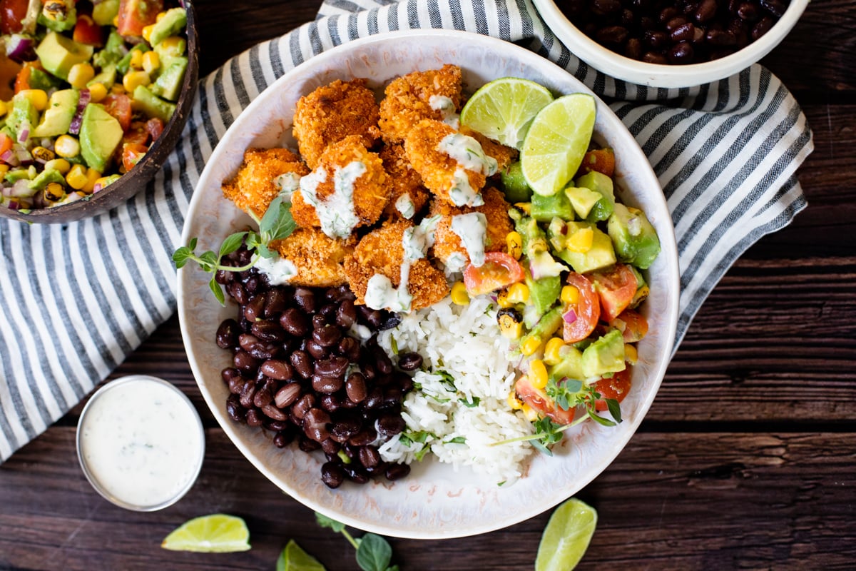 These Coconut Cajun Tofu Bowls are filled with crispy baked tofu, cilantro lime rice, black beans, avocado salsa and a creamy vegan cilantro sauce | ThisSavoryVegan.com #thissavoryvegan #tofubowls #vegandinnerideas