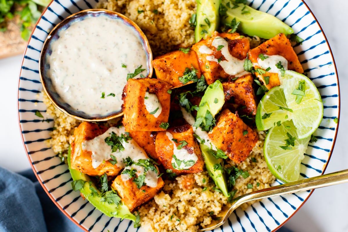 These Buffalo Tofu Couscous Bowls are filled with cilantro lime couscous, baked buffalo tofu & avocado. Served with vegan tahini ranch | ThisSavoryVegan.com #thissavoryvegan #tofurecipes #grainbowls