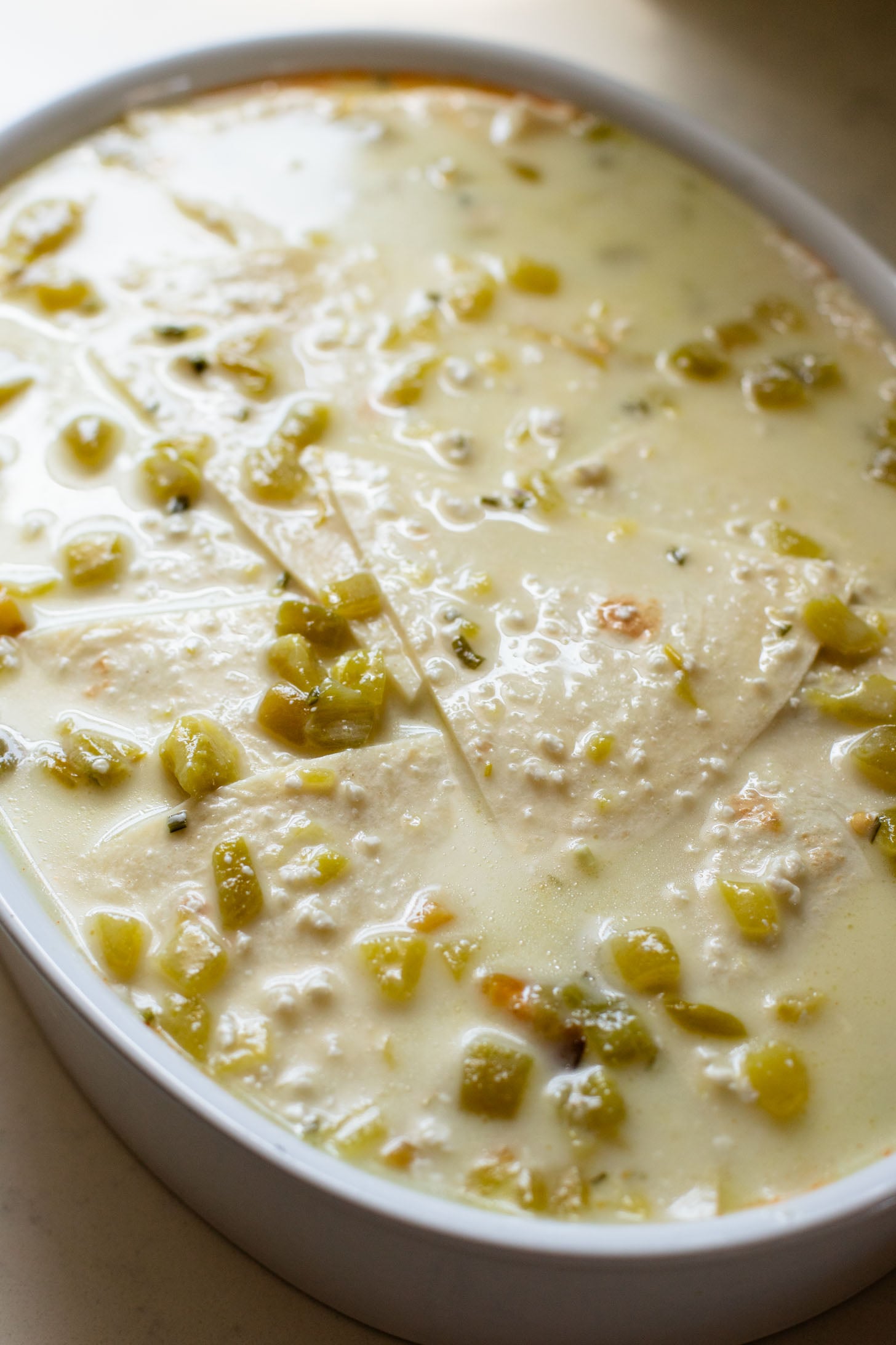 This vegan Green Chile Enchilada Casserole is made with a dairy-free sour cream sauce, lots of veggies, soyrizo, beans and flour tortillas | ThisSavoryVegan.com #thissavoryvegan #veganenchiladas #dairyfreeenchiladas