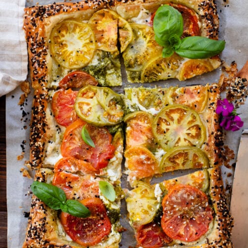 This vegan Heirloom Tomato Tart is made with puff pastry, a creamy non-dairy cheese, pesto & heirloom tomato slices. The perfect summer appetizer or brunch idea | ThisSavoryVegan.com #puffpastryideas #heirloomtomatorecipes #summerrecipes