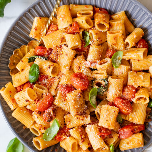 This Spicy Burst Tomato Pasta is a simple vegan pasta recipe made with cherry tomatoes, lots of garlic & basil and chili crisp oil for some heat | ThisSavoryVegan.com #thissavoryvegan #veganpasta #spicypasta
