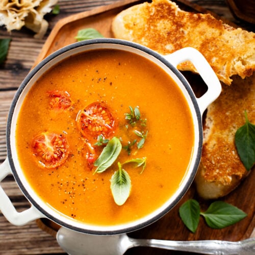This Roasted Garlic Tomato Soup is creamy, savory & delicious. Served with vegan parmesan toast and topped with fresh basil | ThisSavoryVegan.com #tomatosoup #soupseason #vegansoup