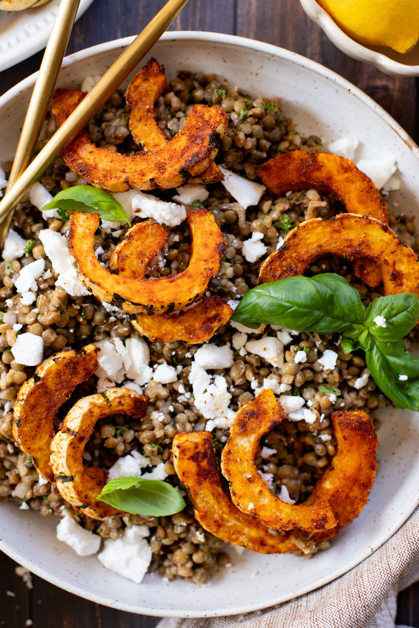 This Roasted Squash & Lentils recipe is a mix between a salad and a bowl. Crispy delicata squash, vegan feta and lemony lentils with fresh herbs | ThisSavoryVegan.com #thissavoryvegan #squashrecipes #fallrecipes