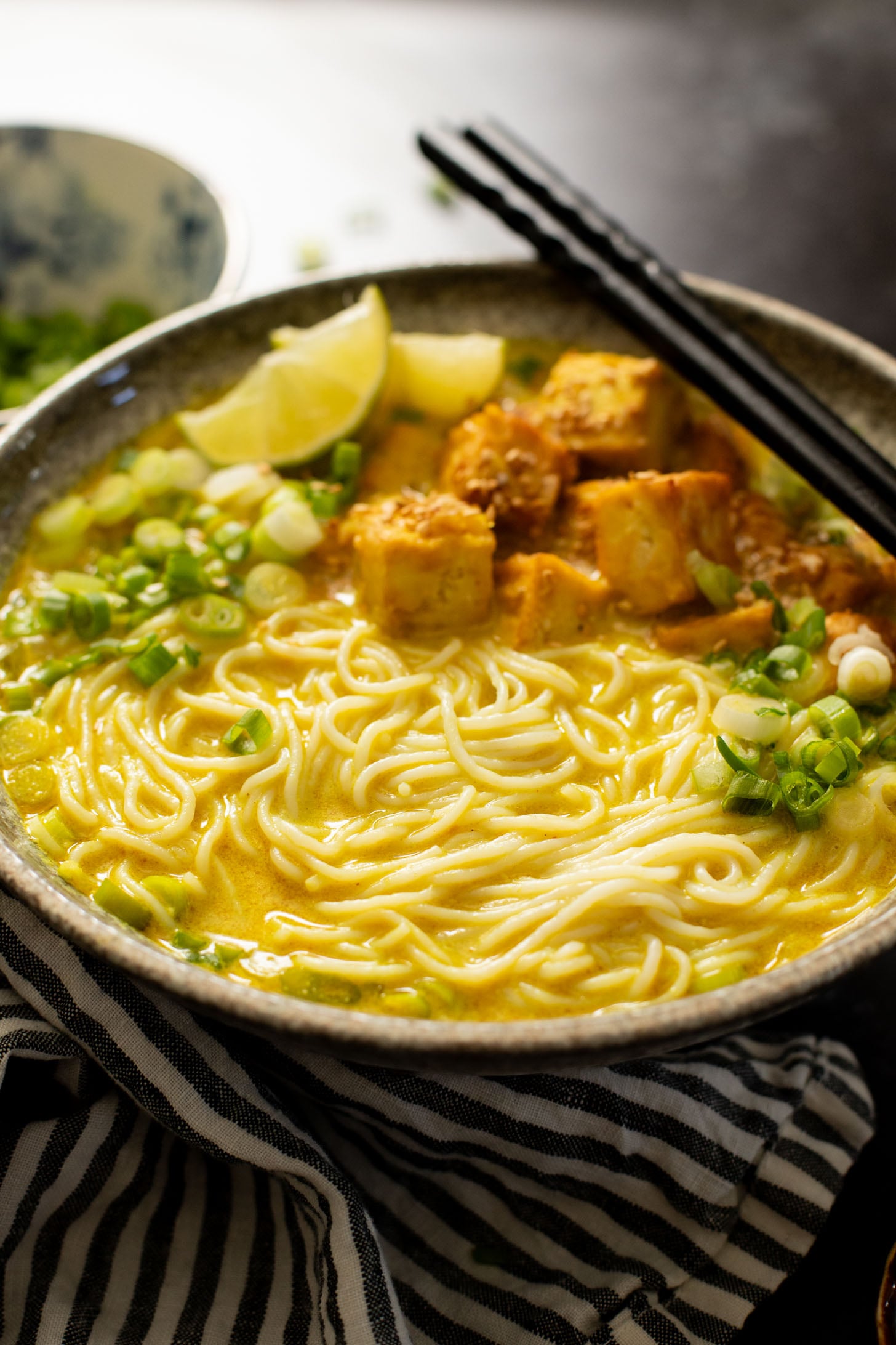 This Golden Coconut Noodle Soup is healthy & heart warming. A coconut curry broth, crispy baked tofu & tender rice noodles | ThisSavoryVegan.com #vegansoup #noodlesoup #healthysoup