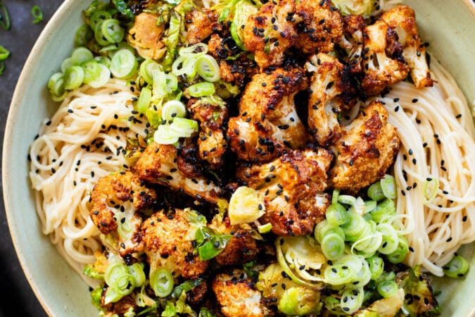 This Hoisin Cauliflower & Coconut Rice Noodles recipe is better than takeout! Coconut rice noodles are topped with crispy cauliflower & roasted brussels sprouts | ThisSavoryVegan.com #thissavoryvegan #cauliflowerrecipes #vegantakeoutrecipes