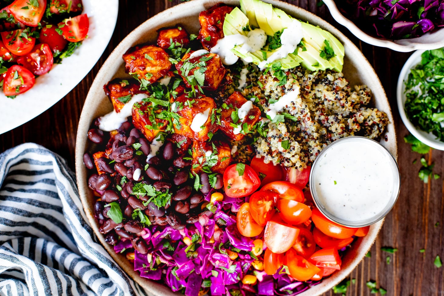 These BBQ Tofu Quinoa Bowls are layered with saucy BBQ tofu, quinoa, black beans, corn & cabbage slaw, tomatoes, avocado & vegan ranch | ThisSavoryVegan.com #thissavoryvegan #quinoabowl #easyveganrecipes