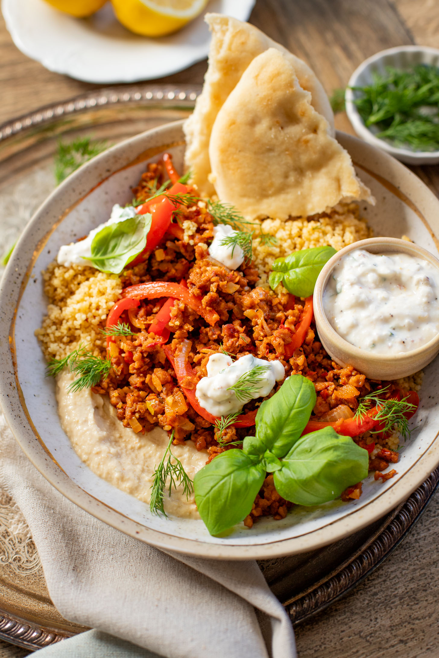These Vegan Harissa Beef Couscous Bowls are layered with lemon couscous, hummus, veggies, "beef" crumbles and vegan feta sauce | ThisSavoryVegan.com
