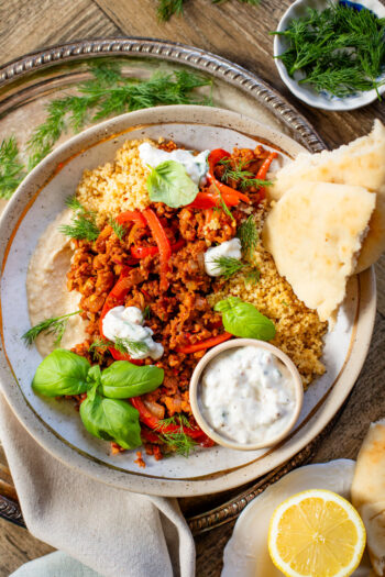 These Vegan Harissa Beef Couscous Bowls are layered with lemon couscous, hummus, veggies, "beef" crumbles and vegan feta sauce | ThisSavoryVegan.com