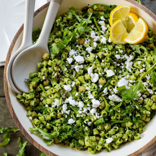 This Kale Pesto Pasta Salad is made with a dairy-free, earthy kale & basil pesto, vegan feta, chickpeas, sun-dried tomatoes & arugula | ThisSavoryVegan.com