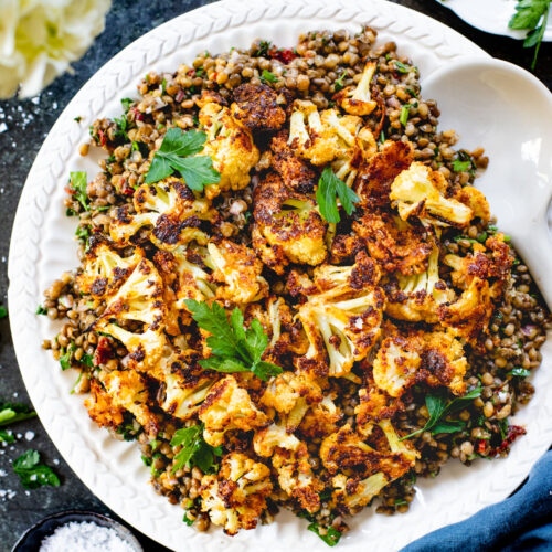 This Parmesan Cauliflower & Lentil Salad is 100% vegan. The cauliflower is coated in vegan parmesan & roasted until crispy. Served over a fresh lentil salad | ThisSavoryVegan.com