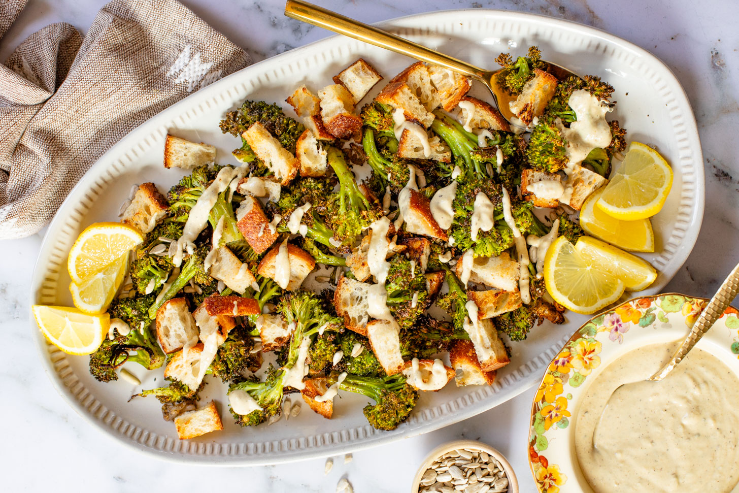 This Roasted Broccoli Salad is layered with crispy shallots & broccoli, garlic croutons, sunflower seeds and lemon tahini dressing | ThisSavoryVegan.com