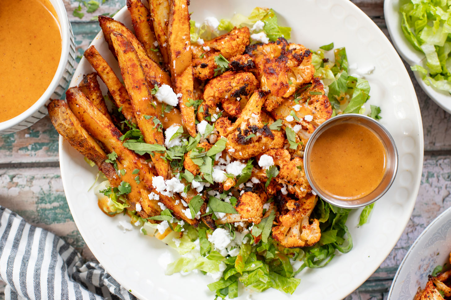 These Roasted Cauliflower & Potato Bowls are layered with seasoned roasted veggies, fresh romaine & a chipotle agave vinaigrette | ThisSavoryVegan.com