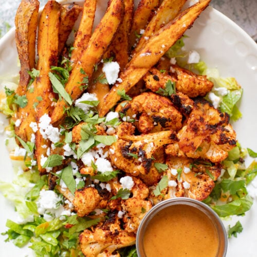 These Roasted Cauliflower & Potato Bowls are layered with seasoned roasted veggies, fresh romaine & a chipotle agave vinaigrette | ThisSavoryVegan.com
