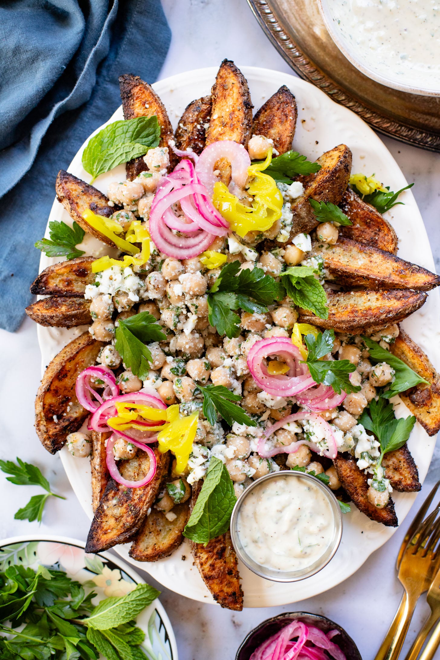 These Loaded Greek Potato Wedges are a great vegan meal idea. Marinated chickpeas, vegan feta, crispy potato wedges & a tahini sauce | ThisSavoryVegan.com