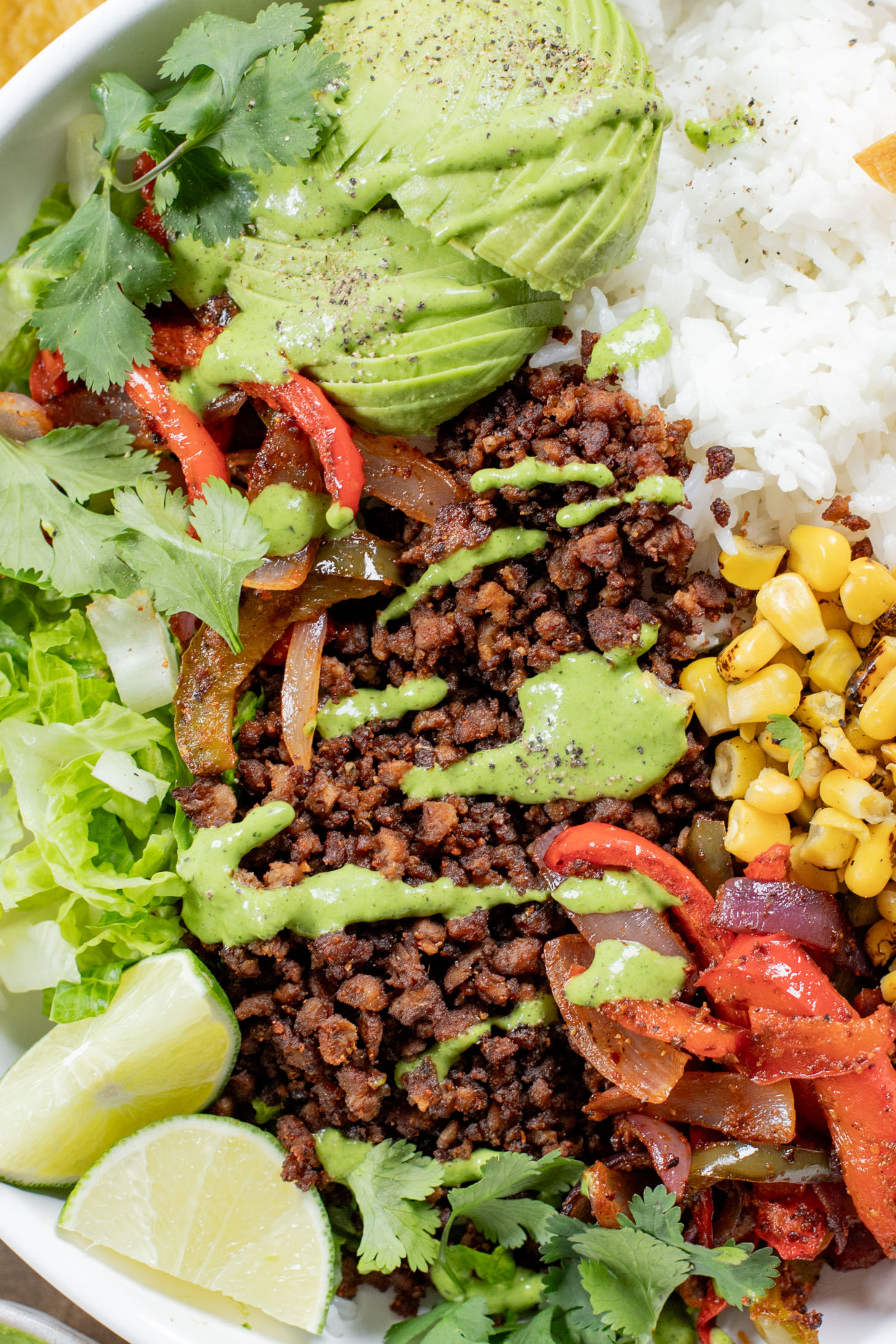 A quick & easy vegan dinner idea, these Sheet Pan Burrito Bowls are filled with vegan "beef" crumbles, fajita veggies & a cilantro yogurt sauce | ThisSavoryVegan.com