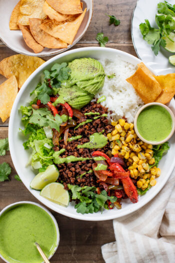 A quick & easy vegan dinner idea, these Sheet Pan Burrito Bowls are filled with vegan "beef" crumbles, fajita veggies & a cilantro yogurt sauce | ThisSavoryVegan.com