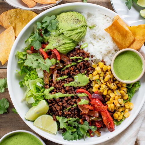 A quick & easy vegan dinner idea, these Sheet Pan Burrito Bowls are filled with vegan "beef" crumbles, fajita veggies & a cilantro yogurt sauce | ThisSavoryVegan.com