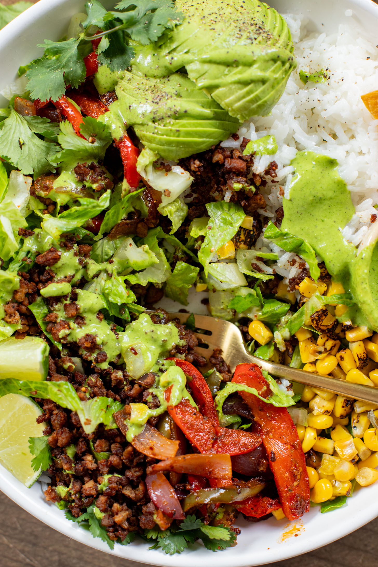 A quick & easy vegan dinner idea, these Sheet Pan Burrito Bowls are filled with vegan "beef" crumbles, fajita veggies & a cilantro yogurt sauce | ThisSavoryVegan.com