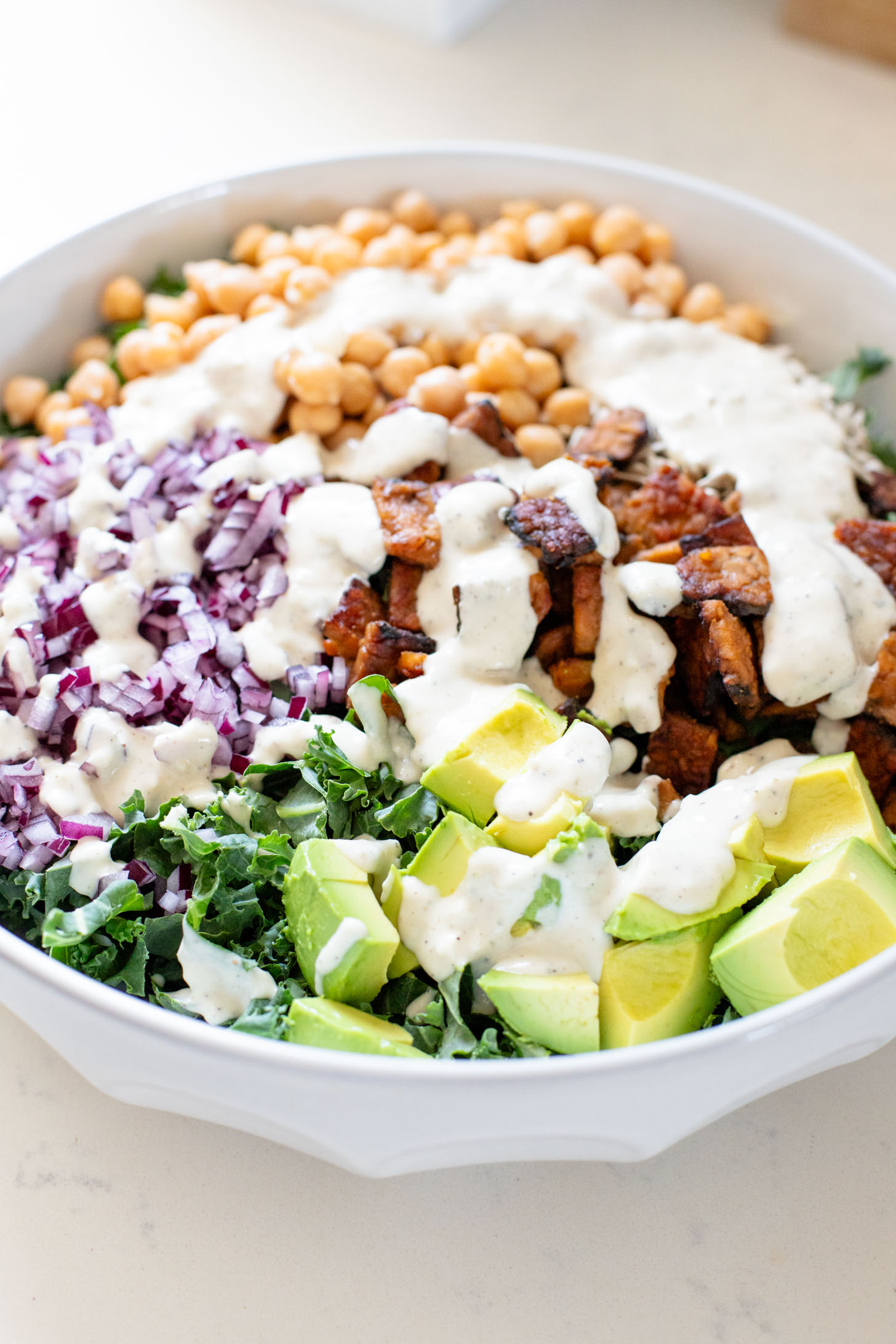 Healthy & delicious, this Tempeh Bacon Kale Salad is a vegan dream! Made with crispy tempeh bacon, chickpeas, avocado & lemon tahini dressing | ThisSavoryVegan.com