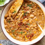 This Creamy White Beans & Soy Chorizo recipe is a cozy one-pot dinner. The beans are simmered in a creamy broth & topped with soy chorizo & corn | ThisSavoryVegan.com