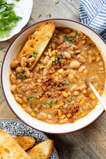 This Creamy White Beans & Soy Chorizo recipe is a cozy one-pot dinner. The beans are simmered in a creamy broth & topped with soy chorizo & corn | ThisSavoryVegan.com
