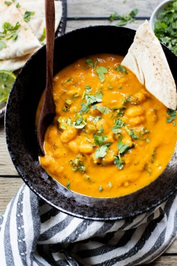 This Curried White Beans & Kale recipe is cozy and veggie packed! Beans are simmered in a coconut & squash sauce to make a delicious vegan curry | ThisSavoryVegan.com