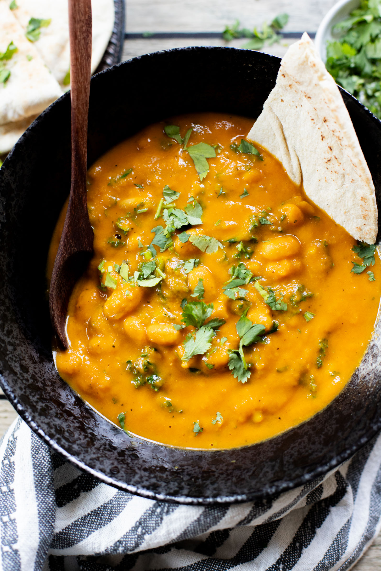 This Curried White Beans & Kale recipe is cozy and veggie packed! Beans are simmered in a coconut & squash sauce to make a delicious vegan curry | ThisSavoryVegan.com