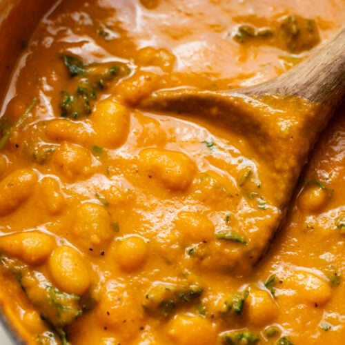 This Curried White Beans & Kale recipe is cozy and veggie packed! Beans are simmered in a coconut & squash sauce to make a delicious vegan curry | ThisSavoryVegan.com