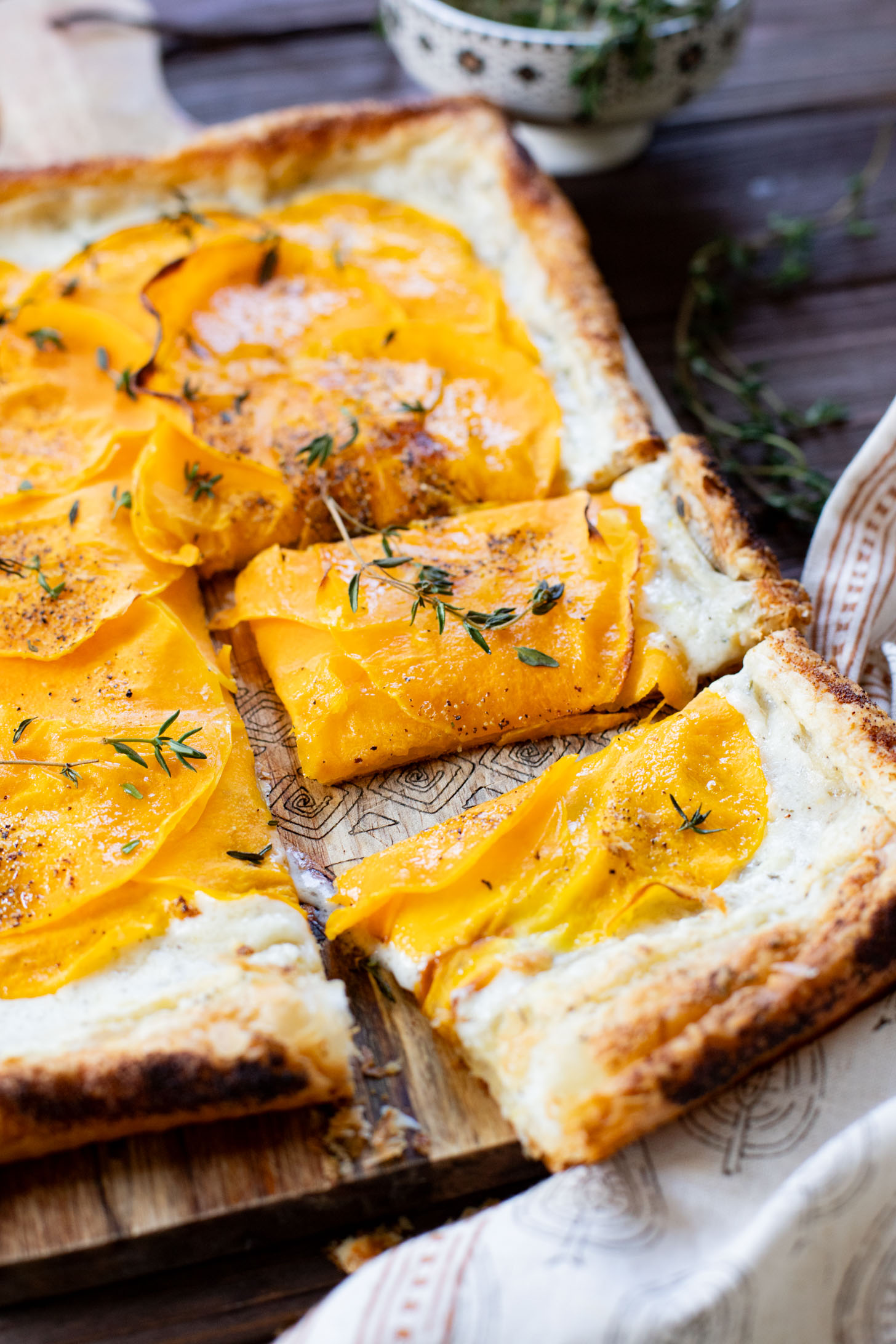 This Cheesy Butternut Squash Tart is the perfect holiday appetizer! Puff pastry is layered with non-dairy cheese and thinly sliced butternut squash | ThisSavoryVegan.com
