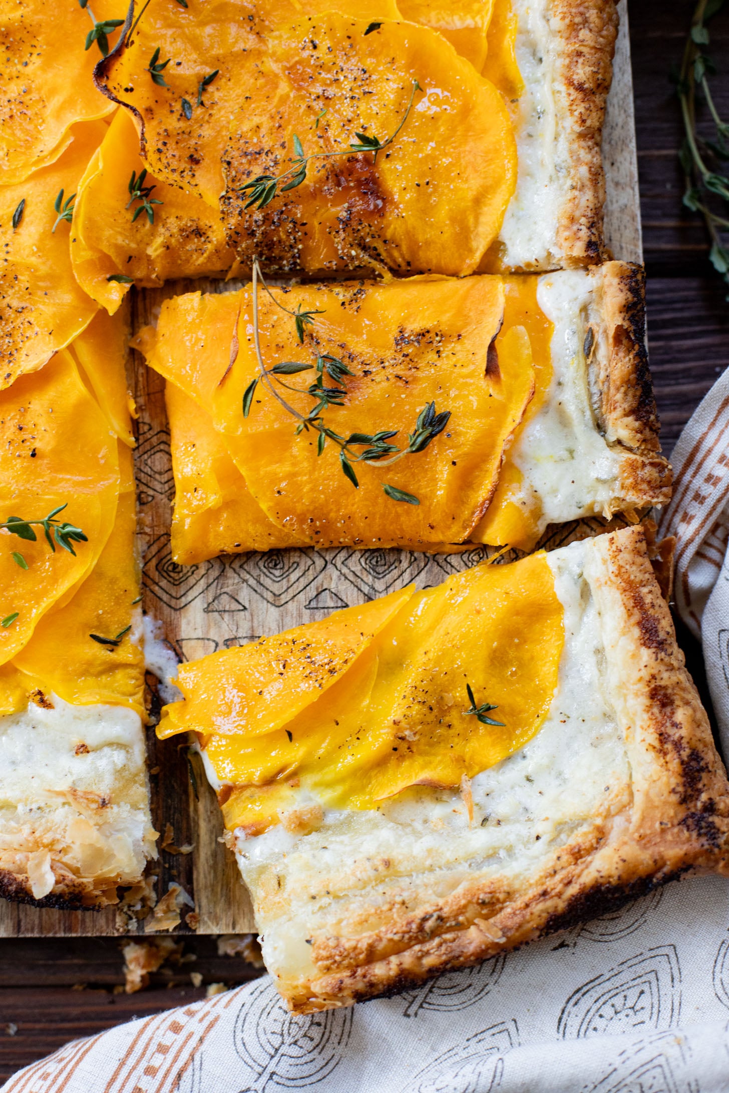 This Cheesy Butternut Squash Tart is the perfect holiday appetizer! Puff pastry is layered with non-dairy cheese and thinly sliced butternut squash | ThisSavoryVegan.com