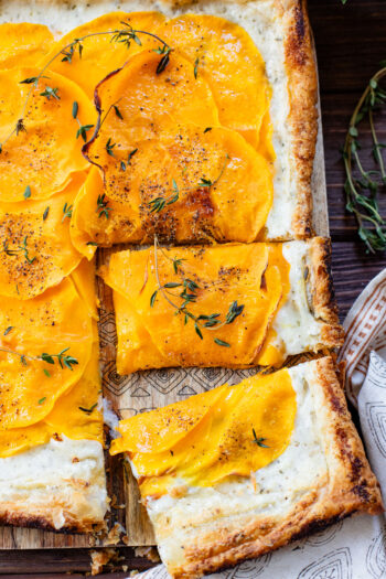 This Cheesy Butternut Squash Tart is the perfect holiday appetizer! Puff pastry is layered with non-dairy cheese and thinly sliced butternut squash | ThisSavoryVegan.com