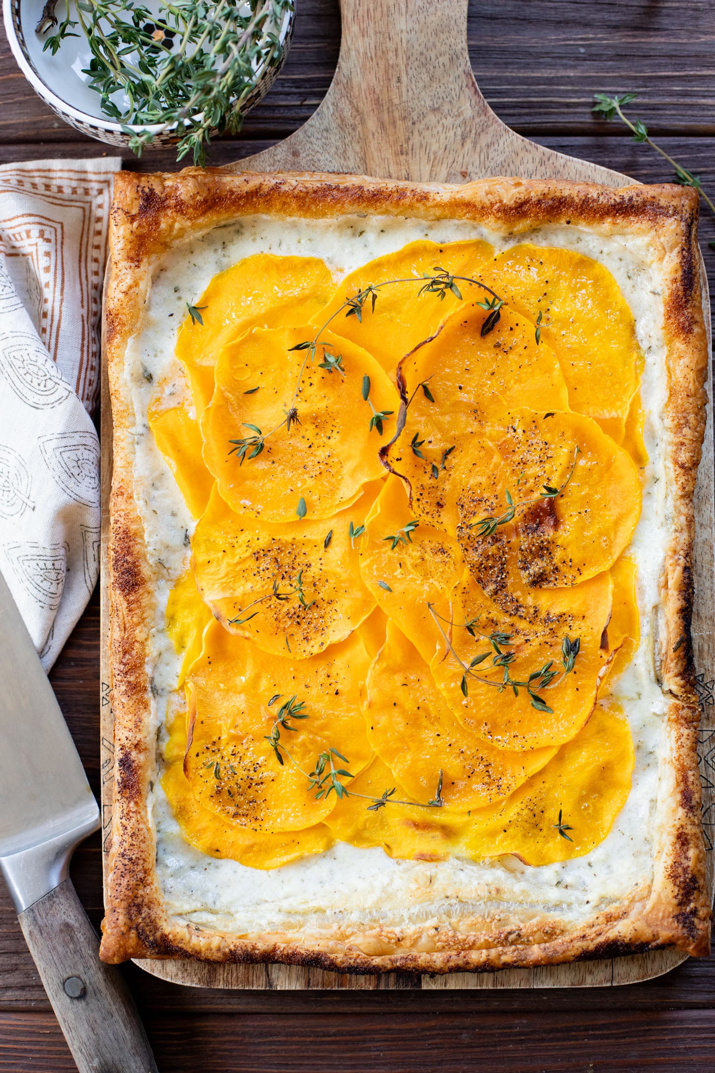 This Cheesy Butternut Squash Tart is the perfect holiday appetizer! Puff pastry is layered with non-dairy cheese and thinly sliced butternut squash | ThisSavoryVegan.com
