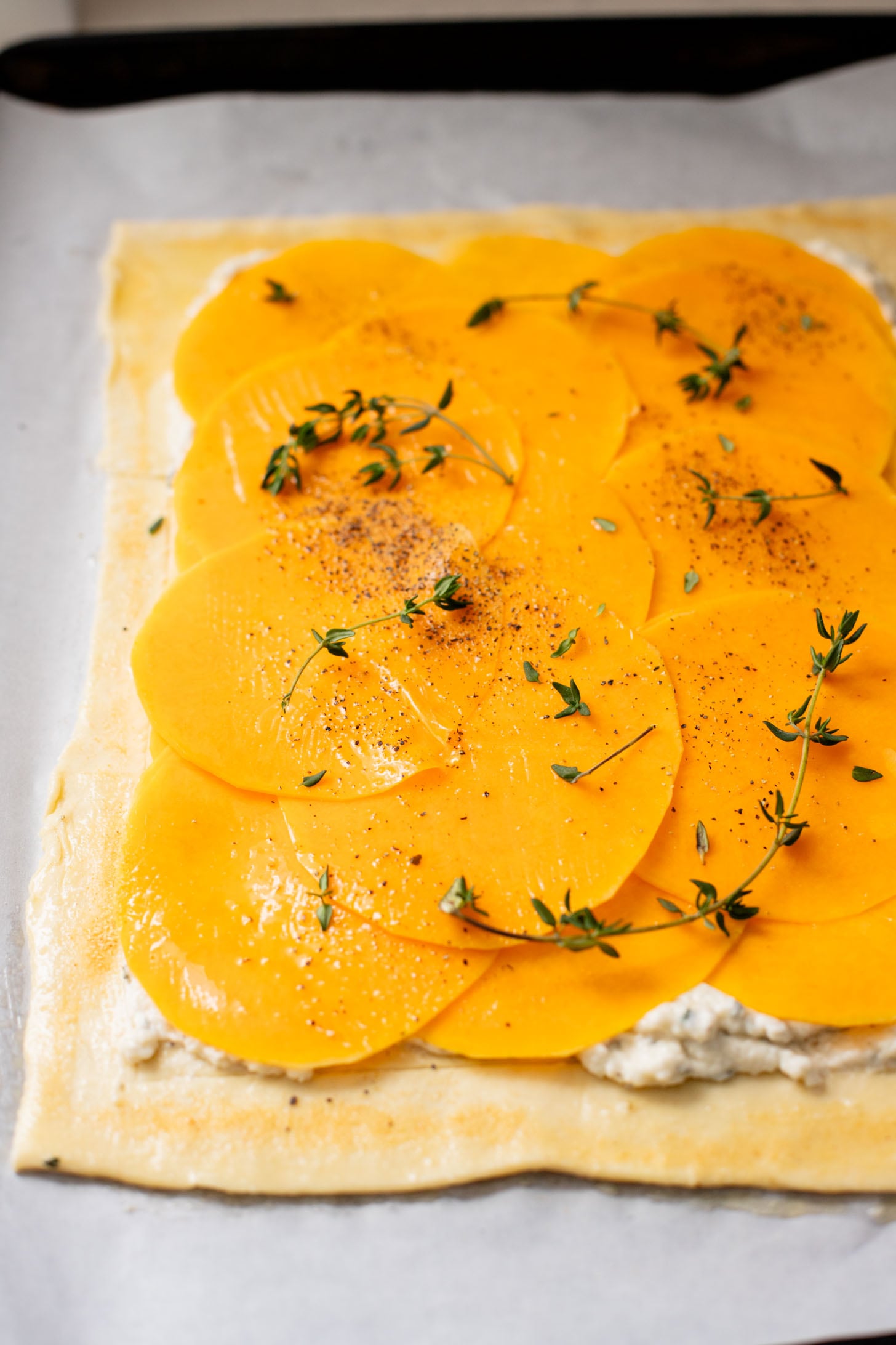 This Cheesy Butternut Squash Tart is the perfect holiday appetizer! Puff pastry is layered with non-dairy cheese and thinly sliced butternut squash | ThisSavoryVegan.com