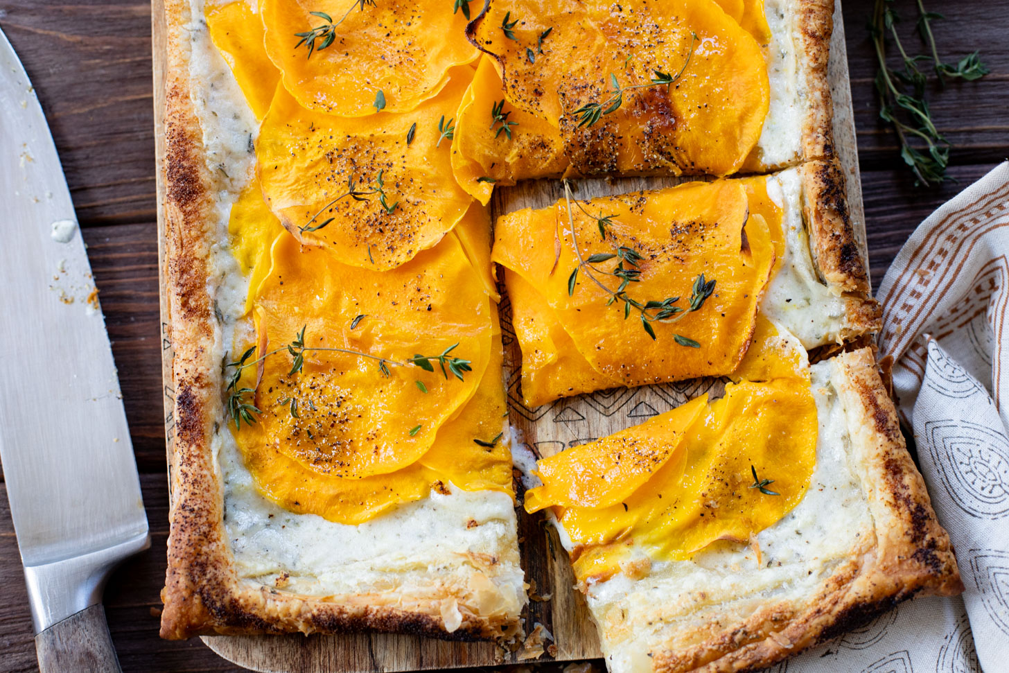 This Cheesy Butternut Squash Tart is the perfect holiday appetizer! Puff pastry is layered with non-dairy cheese and thinly sliced butternut squash | ThisSavoryVegan.com