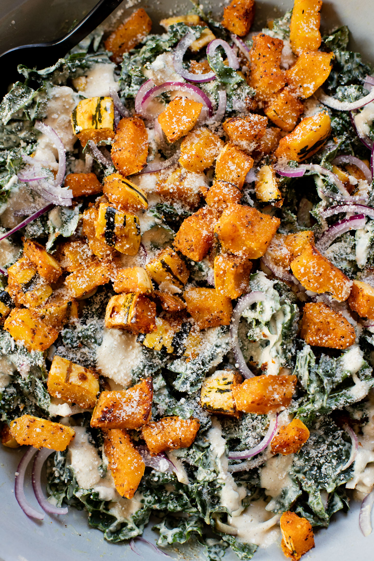 This Fall Harvest Salad is filled with roasted delicata squash, kale & red onion tossed in a creamy tahini dressing. Serve as a main or a side | ThisSavoryVegan.com