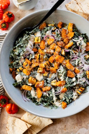 This Fall Harvest Salad is filled with roasted delicata squash, kale & red onion tossed in a creamy tahini dressing. Serve as a main or a side | ThisSavoryVegan.com