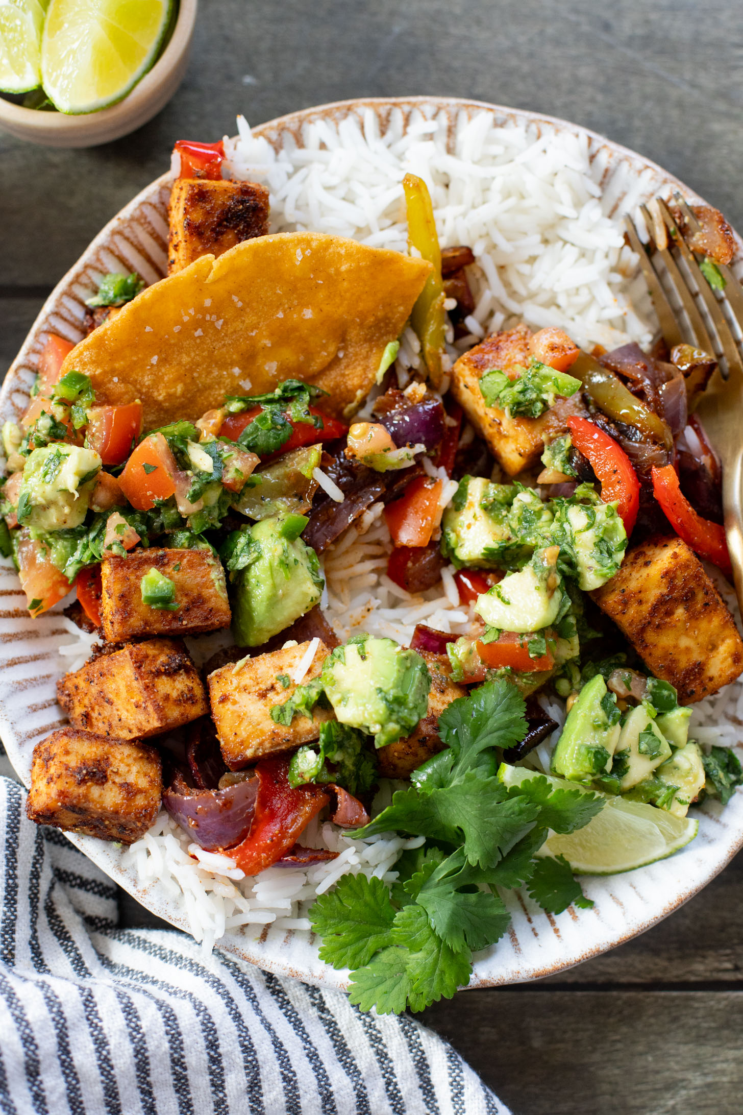These Tofu Fajita Rice Bowls are a quick sheet pan dinner recipe! Packed with protein & veggies, and topped with avocado salsa | ThisSavoryVegan.com