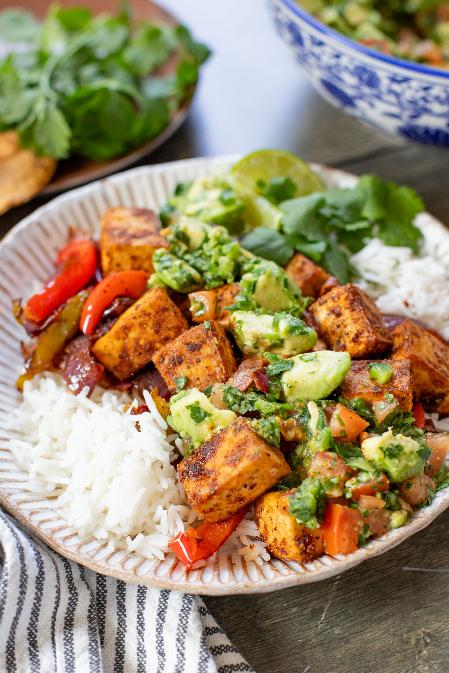 These Tofu Fajita Rice Bowls are a quick sheet pan dinner recipe! Packed with protein & veggies, and topped with avocado salsa | ThisSavoryVegan.com